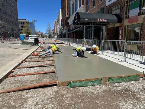 Workers pave the widened concrete sidewalk for Tejon St.